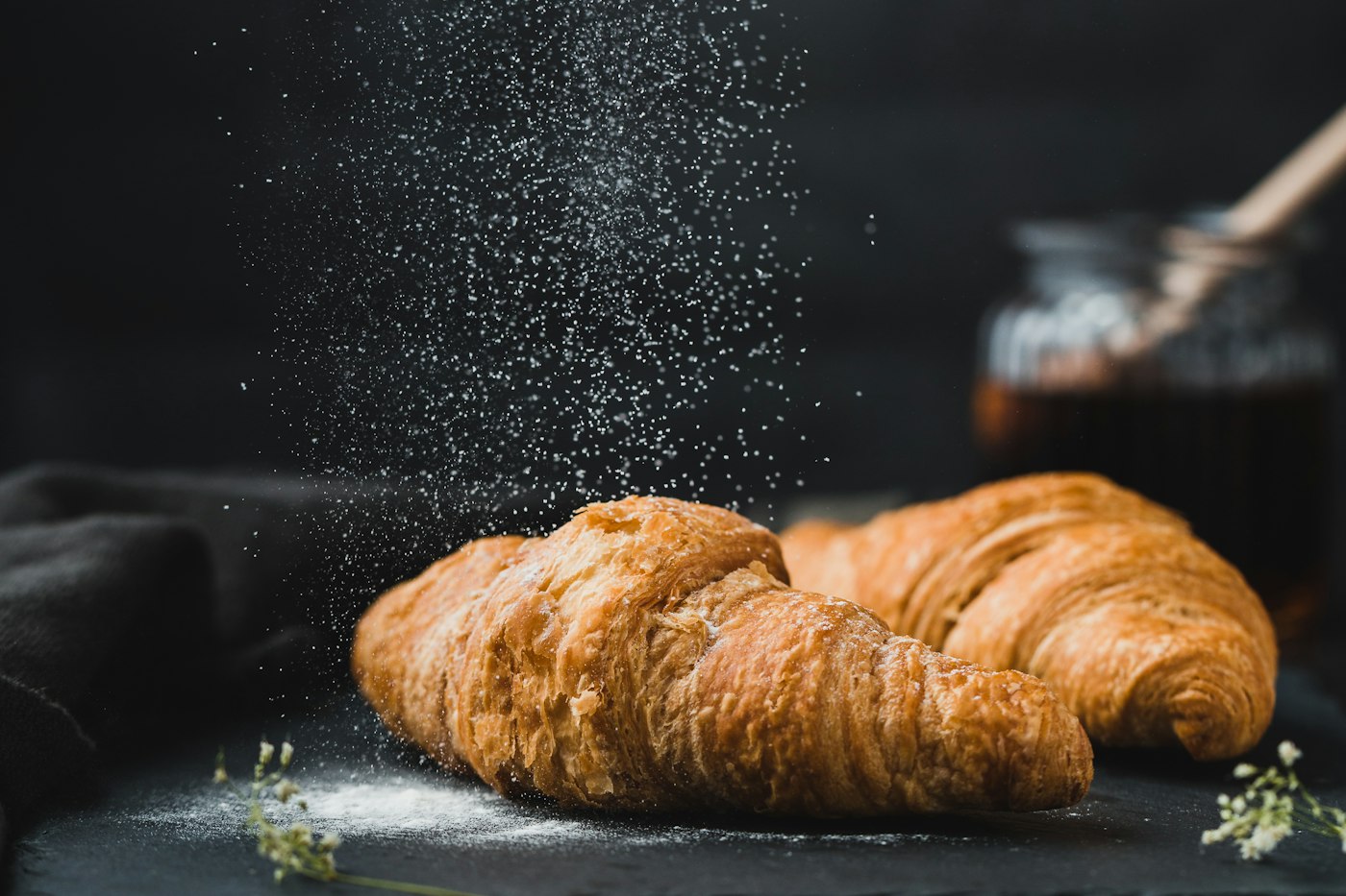 Fresh croissants being dusted with powdered sugar